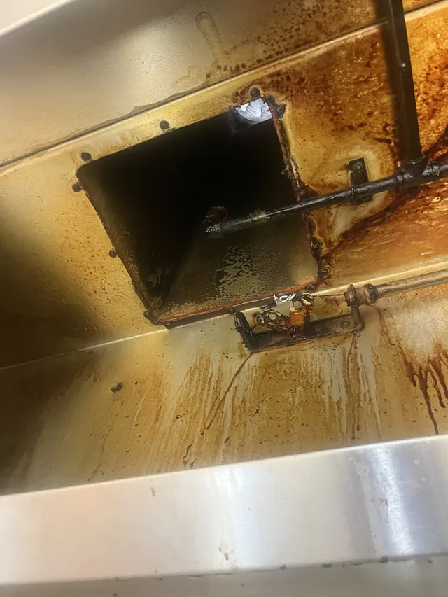 Close view of grease buildup around the rectangular duct opening before cleaning.