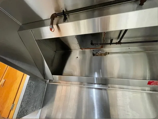 Cleaned hood interior around the duct opening, viewed from below.