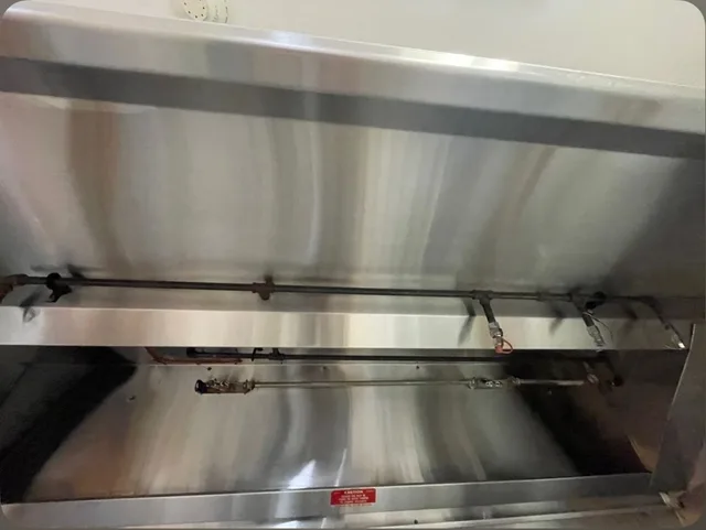 Cleaned stainless steel hood interior beneath the fire suppression pipework.