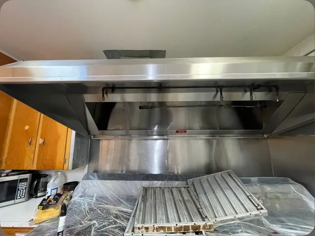 Wide view of the cleaned hood, with removed filters resting on the covered equipment below.
